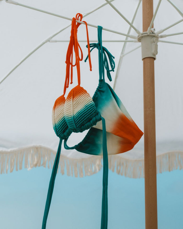 orange and green macrame bikini hanging from an outdoor umbrella