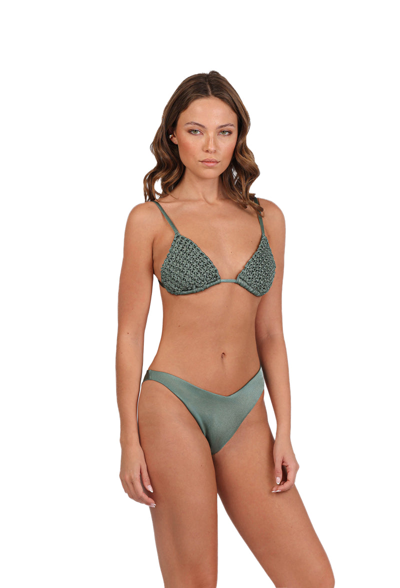 A person modeling the Rio Macrame Triangle Bikini Top stands against a plain white background. The bikini top showcases handcrafted elegance with its textured macramé design, while the bottom remains solid green. The individual has wavy hair and a neutral expression, perfectly suited for chic beachwear.