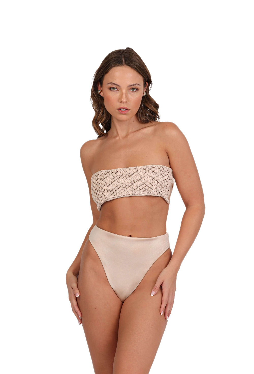 A woman with wavy hair is showcasing beach fashion in the Tia Macrame Strapless Bikini Top paired with high-waisted bottoms. The handmade bikini features a textured pattern on the top as she poses against a plain white background.