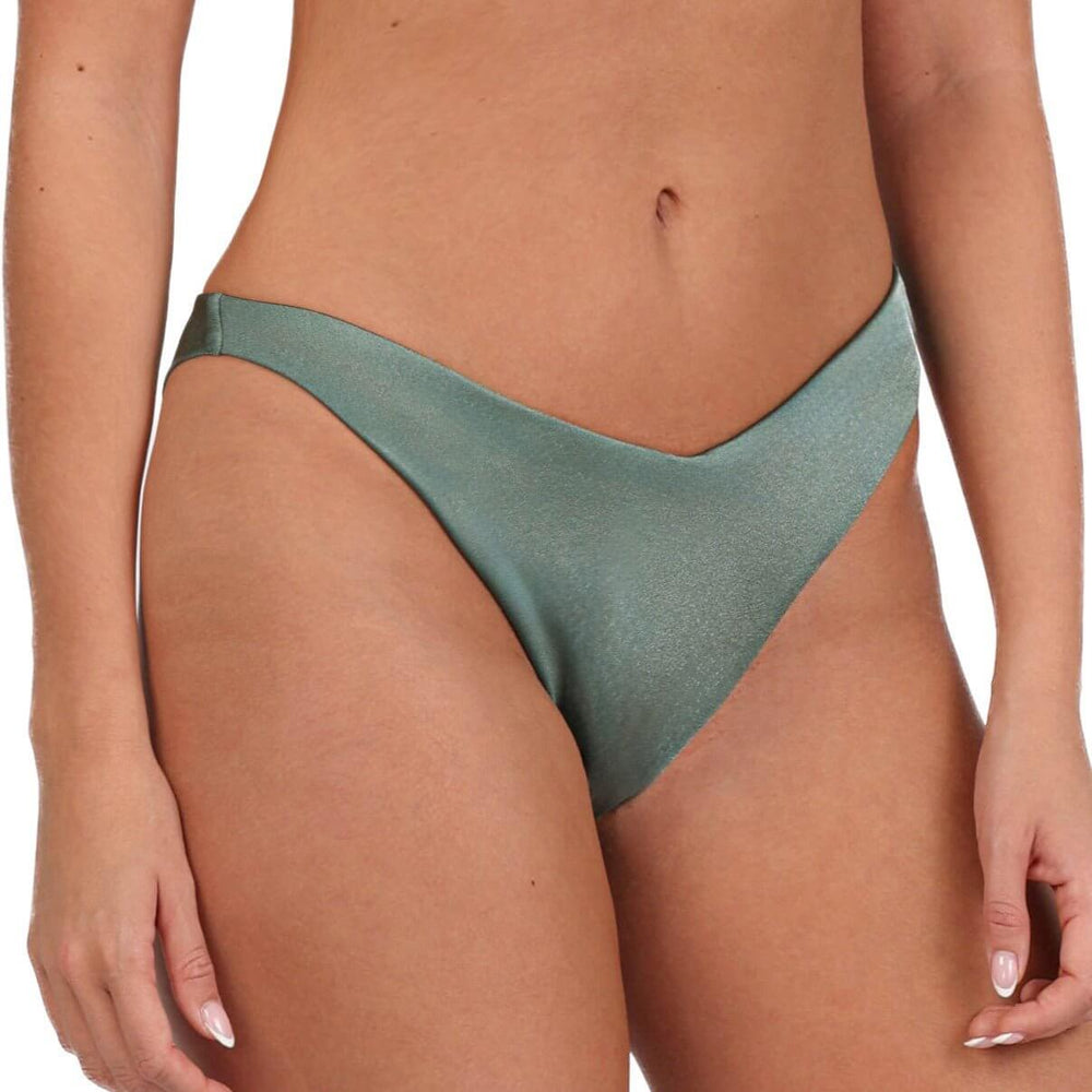 In focus is an individual wearing the Rio Cheeky Bikini Bottom, a high-cut, shimmery green piece with a flattering fit. The emphasis is on the swimwear's texture and fit, complemented by the visible arms and midsection against a plain white background.