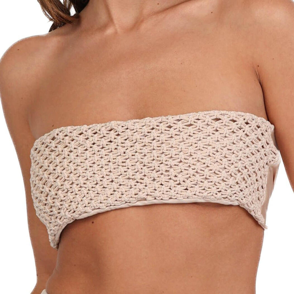 Someone is donning the Tia Macrame Strapless Bikini Top, a beige, crocheted piece that evokes beach fashion. The highlight is its intricate woven design, much like a handmade macrame bikini top, showcased against a simple background.