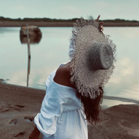 Woman on a beach wearing a straw hat and white dress with a blurred background