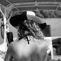Person wearing a wide-brimmed black and white toquilla straw hat while standing outdoors.